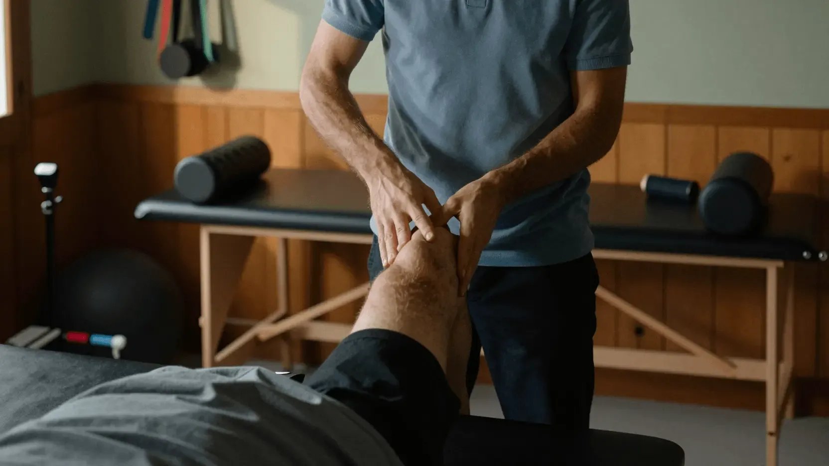 Fisioterapeuta tratando la rodilla de un paciente en la camilla