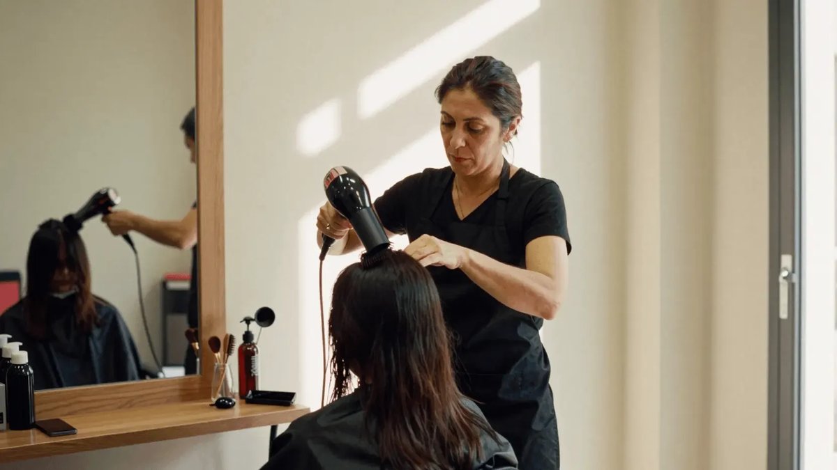 Peluquera secando el pelo a una clienta en un salón