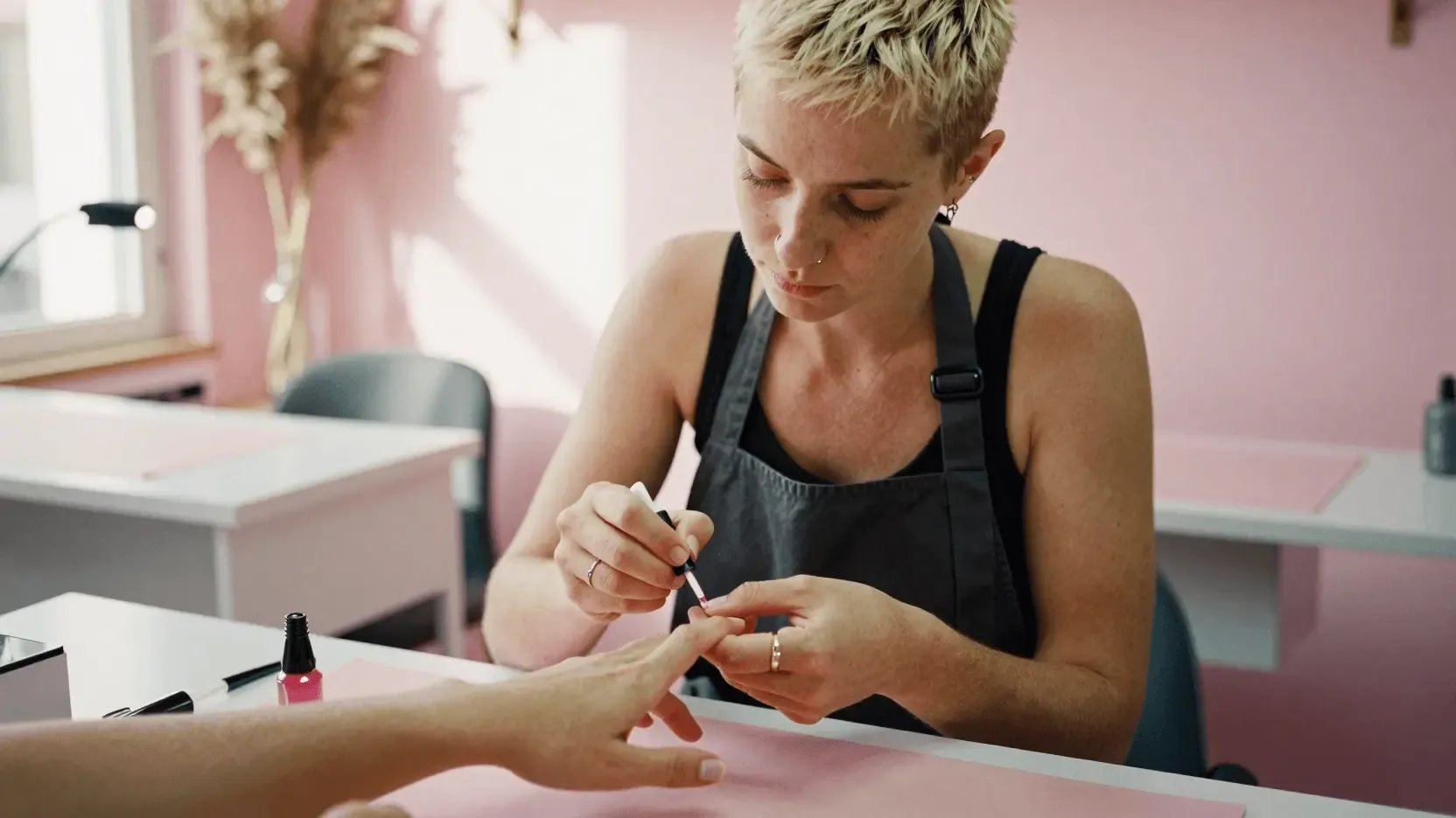 Manicurista pintando las uñas a una clienta en un salón